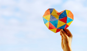 Colored paper heart being held up into the sky
