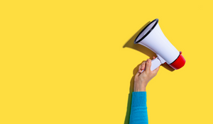 white megaphone being held up against a yellow background